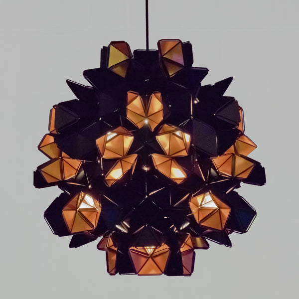 The Labyrinth Lamp is a light sculpture by Republiken. Hang it like a chandelier! The outside of the Labyrinth light sculpture has a matte black surface which contrast the protruding openings where the reflective inside is exposed