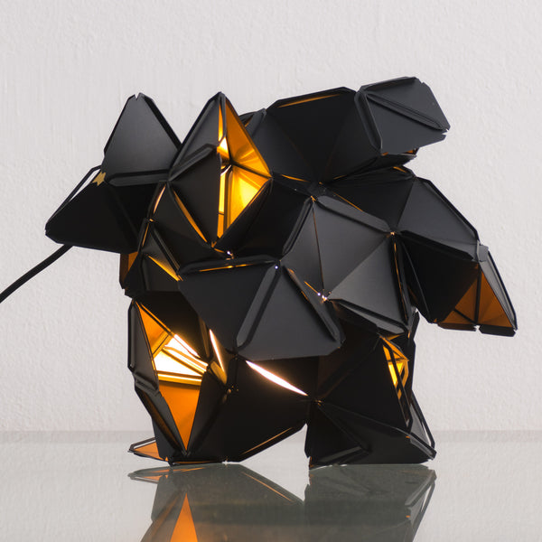 The little Labyrinth lamp is a light sculpture by Republiken. Designed by Jakob Uhlin. Use it as a pendant or as a table light. the golden reflective inside is in strong contrast to the matte black outside. 