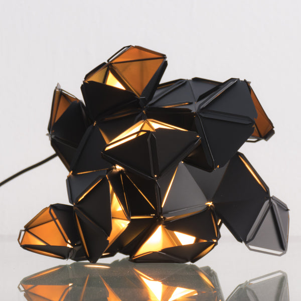 The little Labyrinth lamp is a light sculpture by Republiken. Designed by Jakob Uhlin. Use it as a pendant or as a table light. the golden reflective inside is in strong contrast to the matte black outside. 