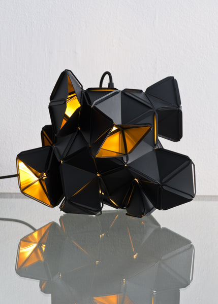The little Labyrinth lamp is a light sculpture by Republiken. Designed by Jakob Uhlin. Use it as a pendant or as a table light. the golden reflective inside is in strong contrast to the matte black outside. 